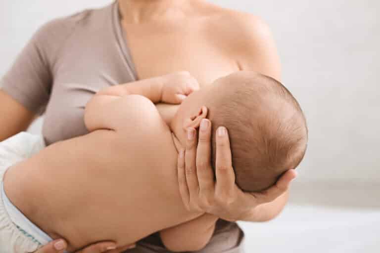 Mother breast feeding and hugging her baby